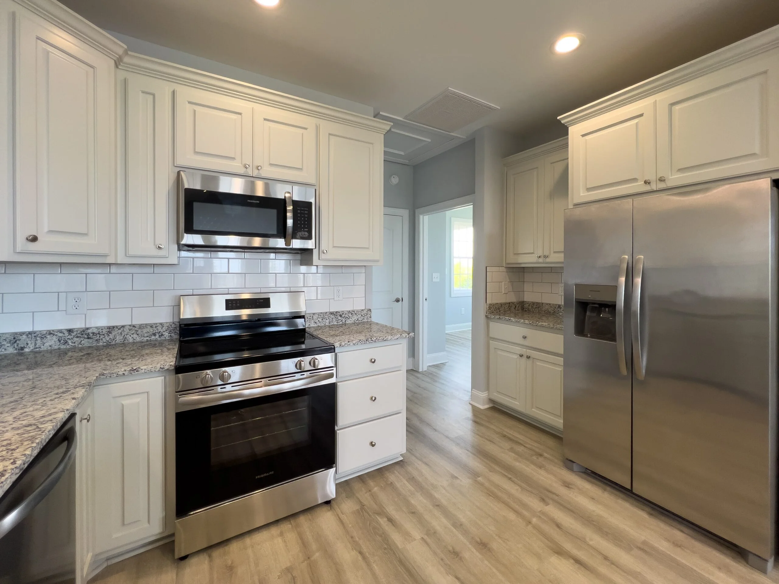 Kitchen with cream cabinetry, granite counters, stainless steel appliances, subway tile backsplash