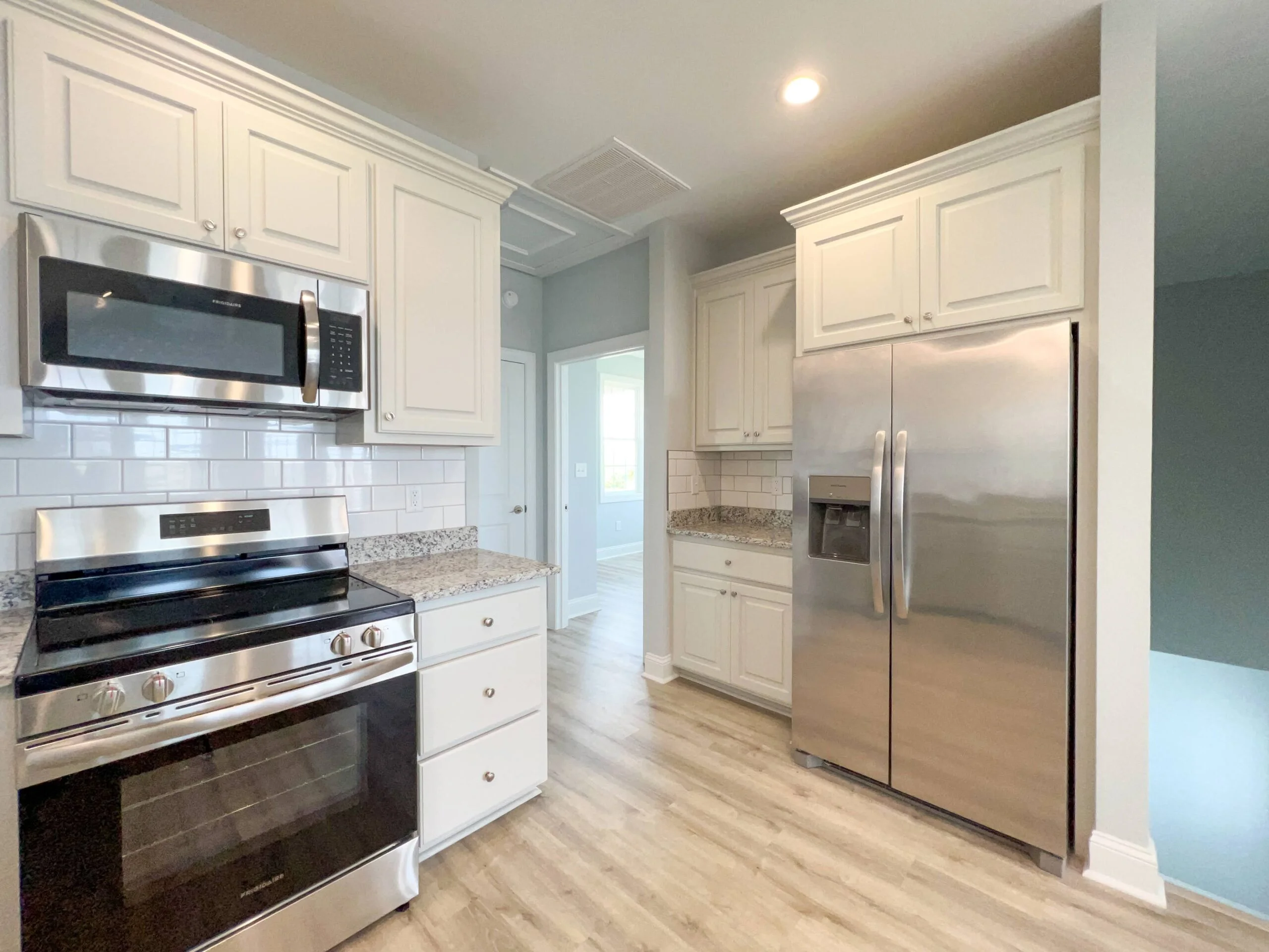 Modern kitchen with white cabinets, stainless steel appliances, granite counters, and subway tile backsplash