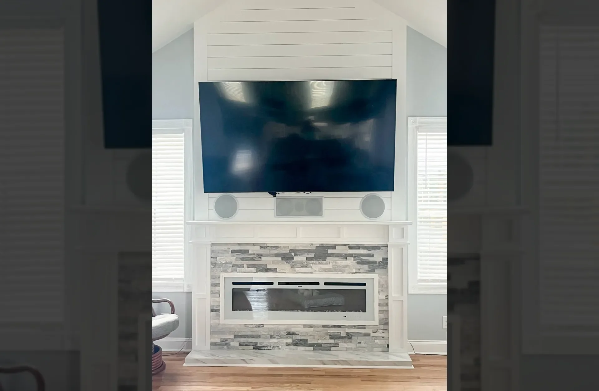 White built-in entertainment wall with stacked stone fireplace, linear insert, and mounted TV