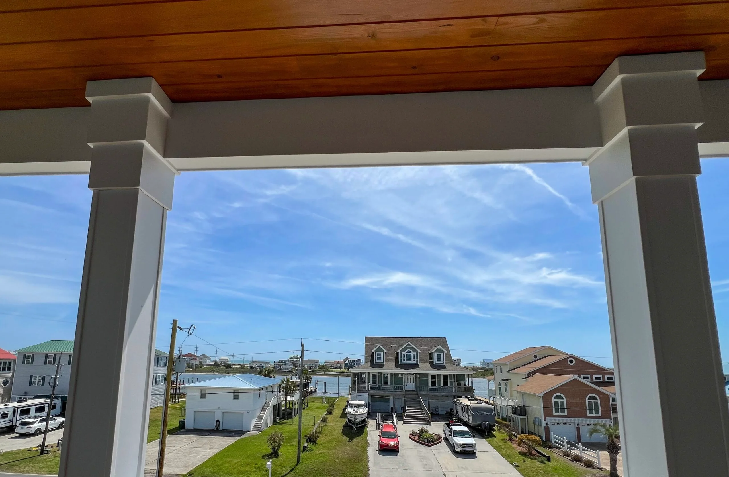 Custom pergola with gray columns and timber ceiling framing waterfront view