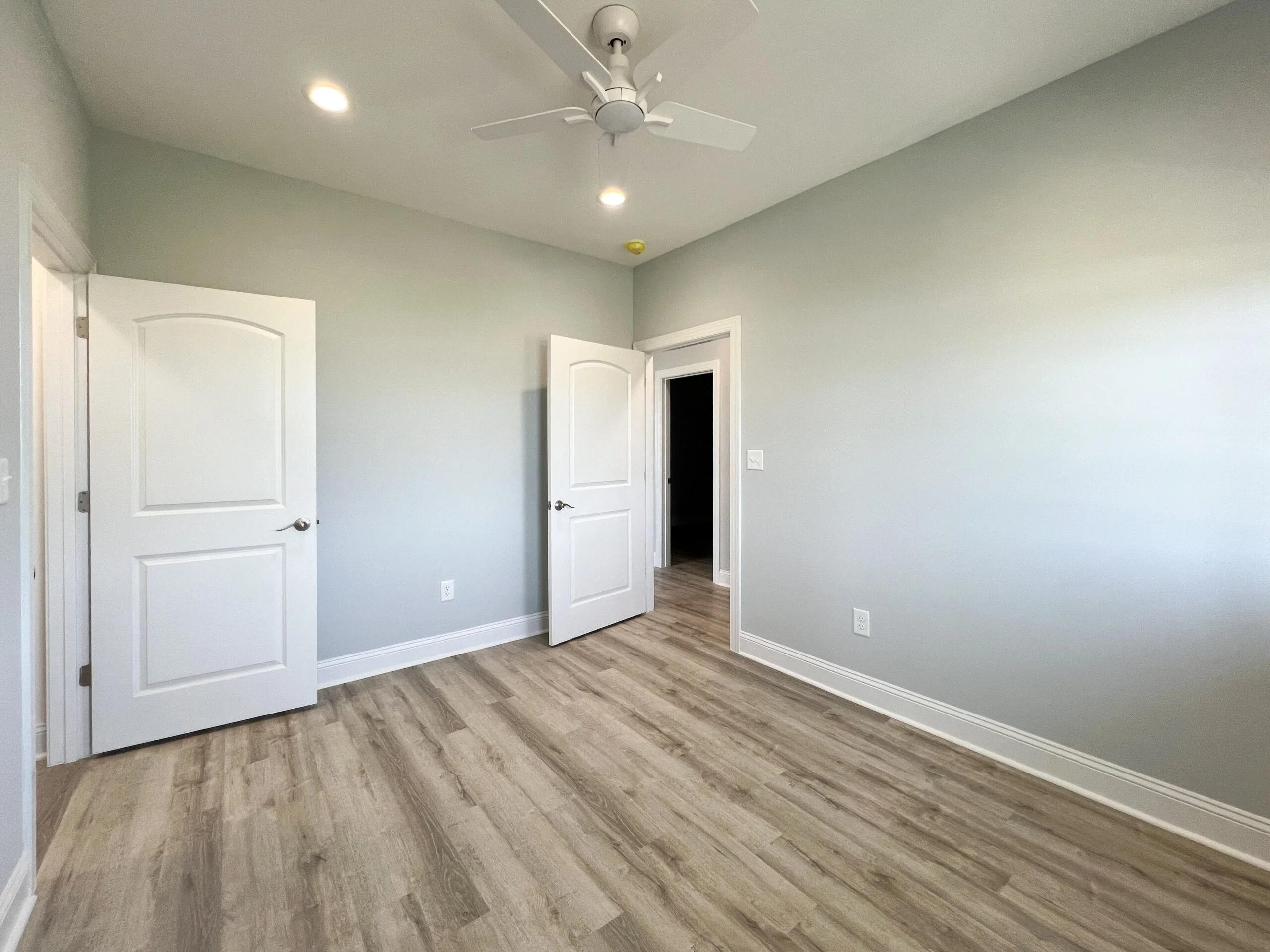 Bedroom with vinyl plank flooring, sage green walls, white doors, recessed lights, and ceiling fan