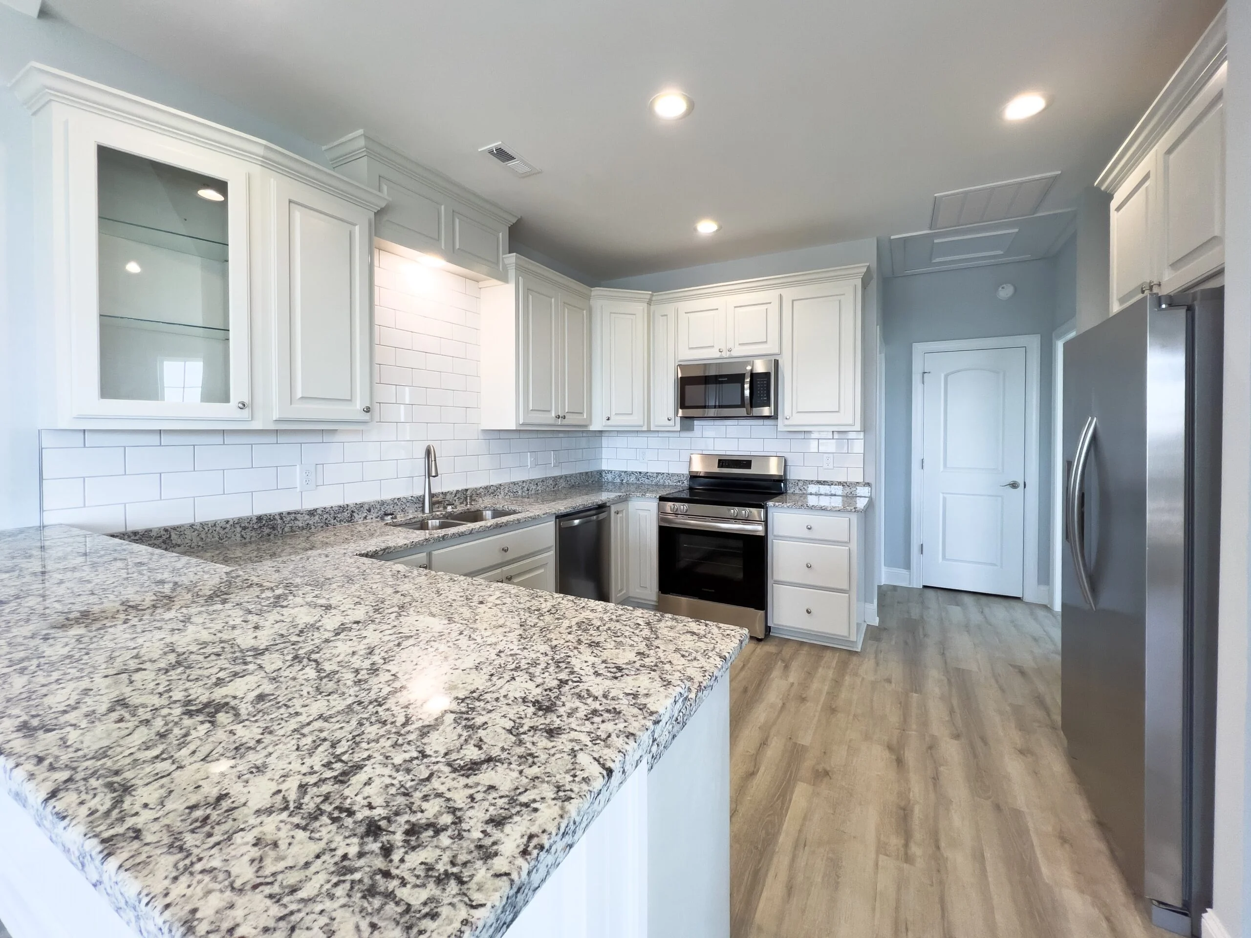White kitchen cabinets, granite countertops, subway tile backsplash, stainless steel appliances