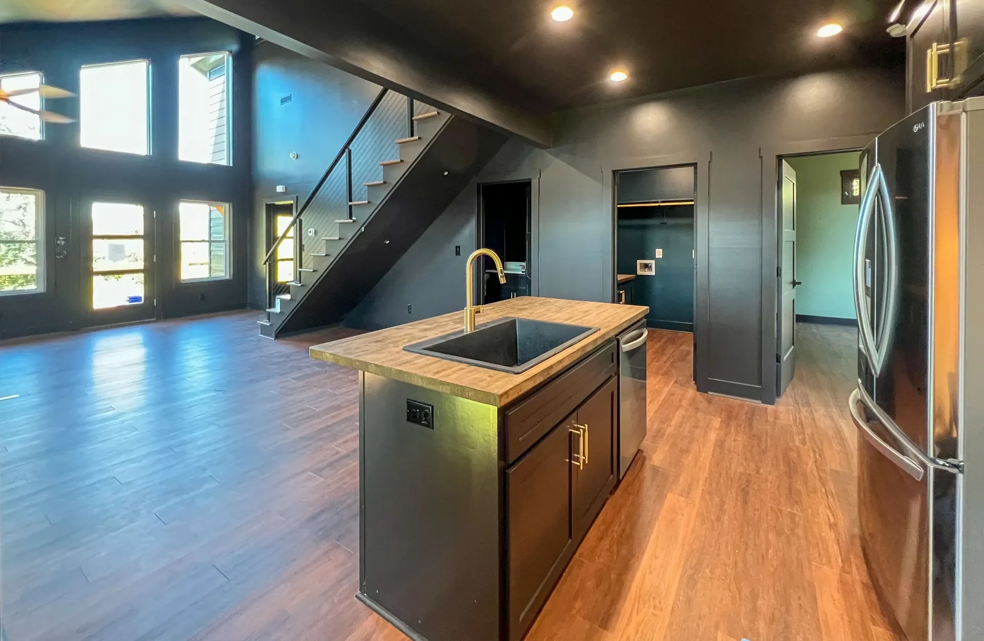 Modern kitchen with wood island, stainless steel appliances, hardwood flooring, and open living area