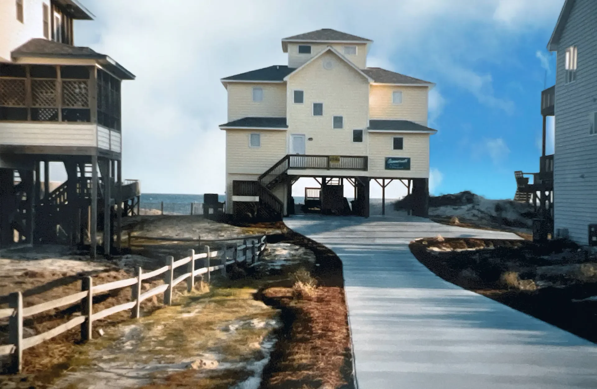 Elevated coastal home with vinyl siding, black pilings foundation, and wraparound deck overlooking water