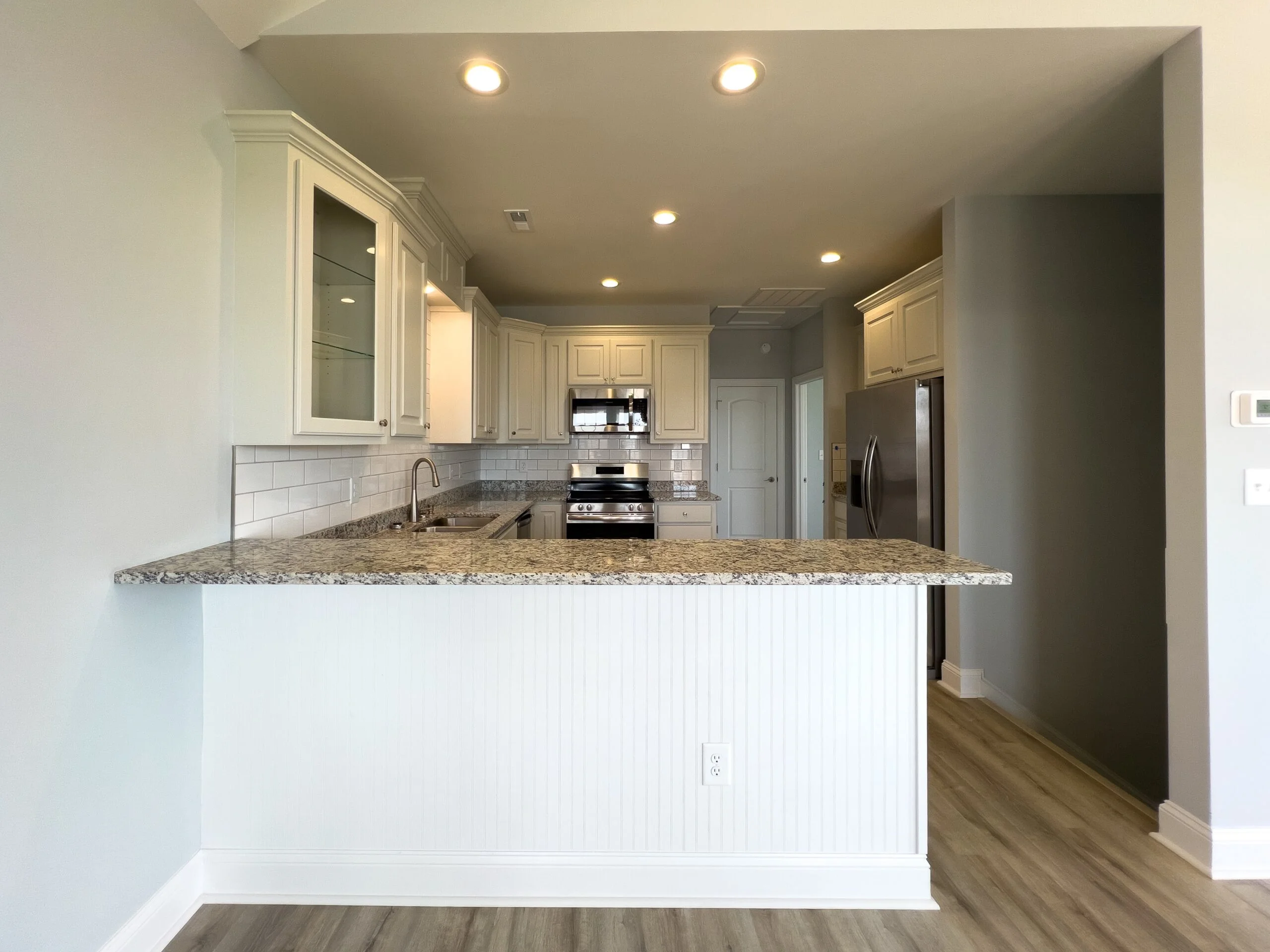 Modern kitchen with white cabinetry, granite counters, subway tile backsplash, and stainless steel appliances