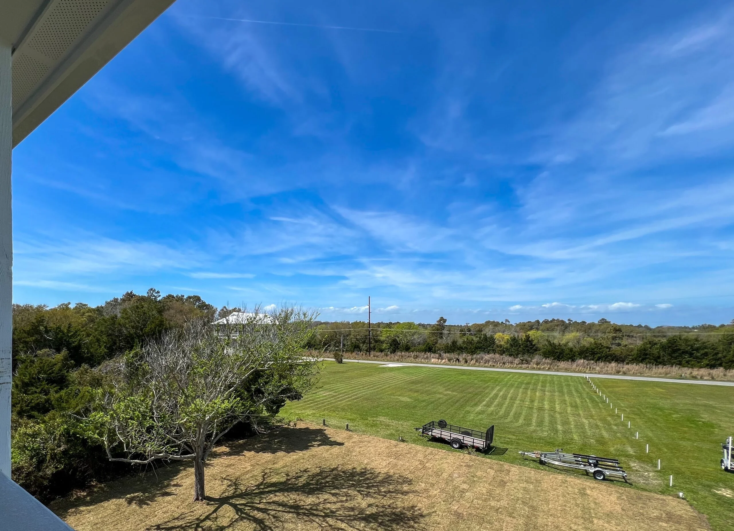 Graded residential lot with striped lawn, cleared building pad, and utility markers on rural property