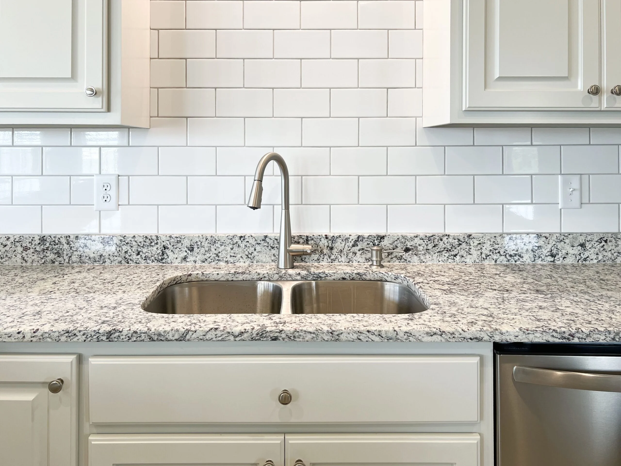 White subway tile backsplash with granite countertop and stainless steel double sink installation
