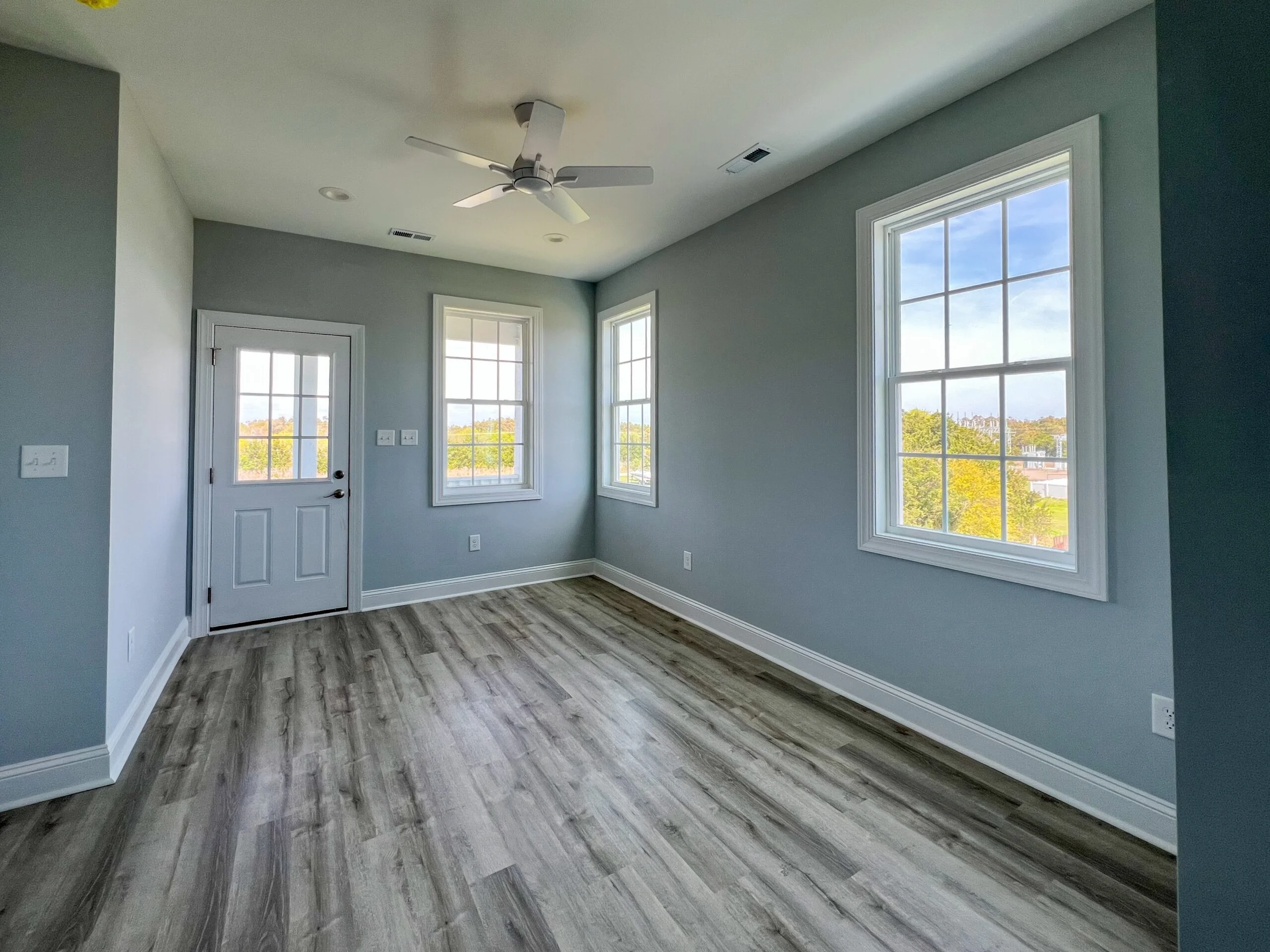Sunroom with vinyl windows, hardwood-look flooring, sage walls, and white trim
