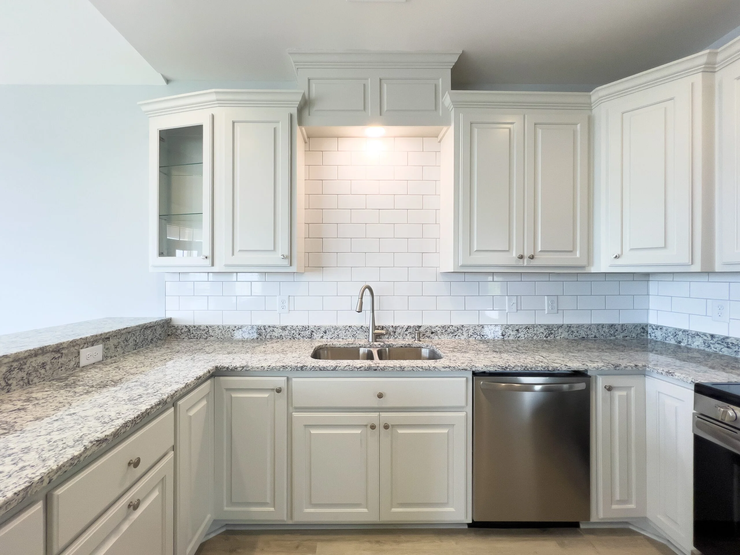 White kitchen cabinets, granite countertops, subway tile backsplash, stainless steel appliances