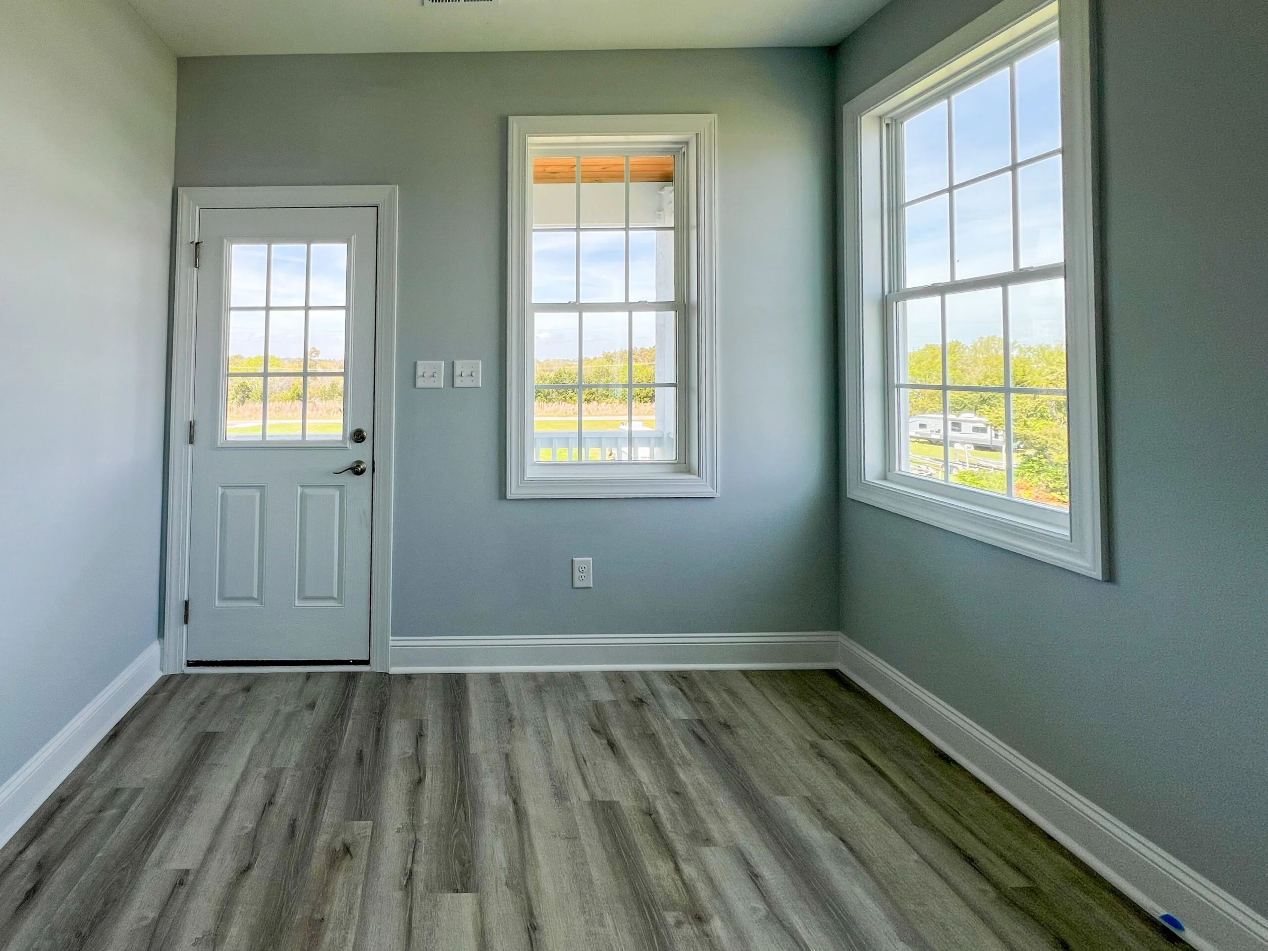 Sunroom with three vinyl windows, exterior door, sage walls, and gray vinyl plank flooring
