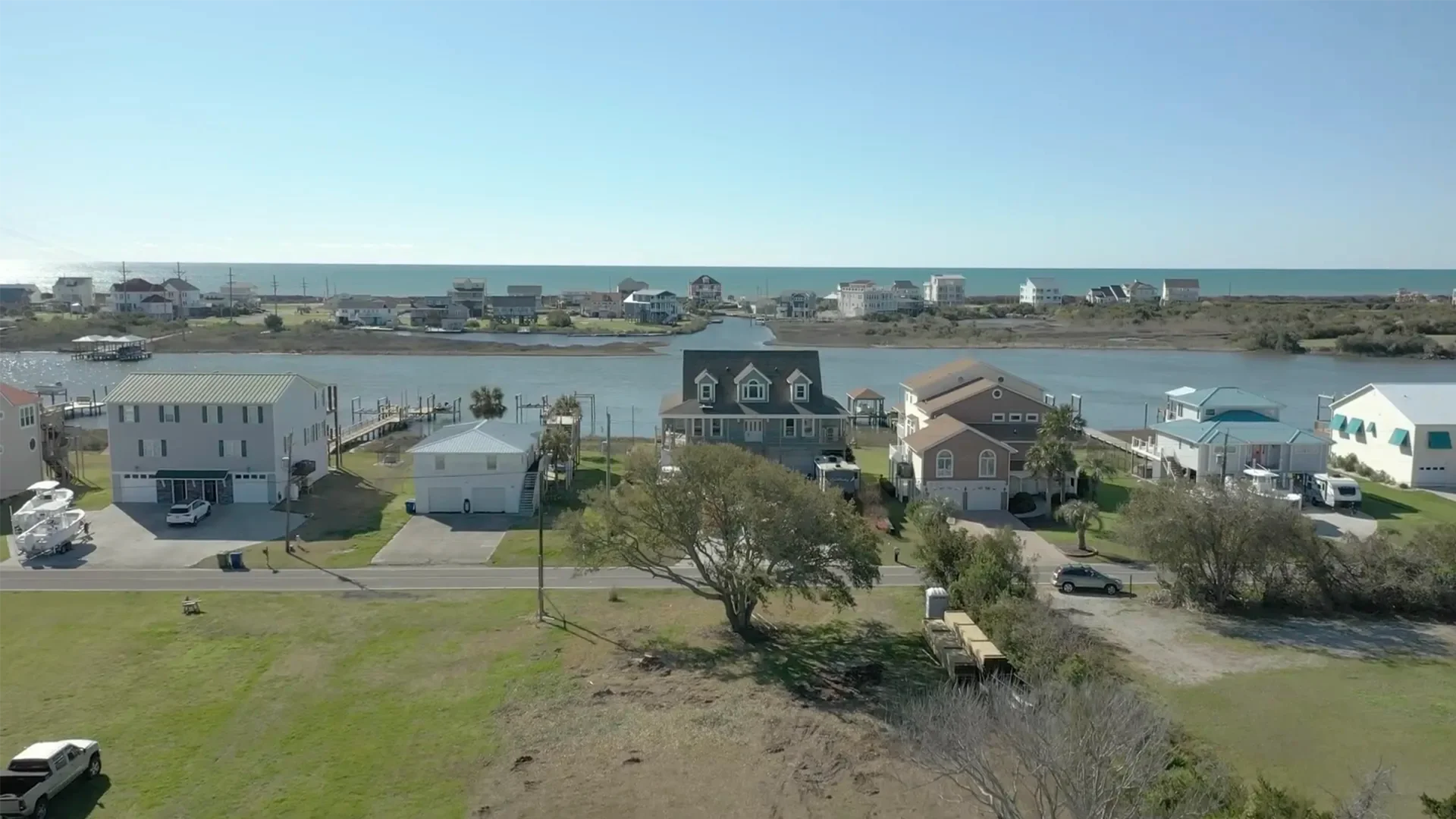 Aerial view of waterfront homes with elevated construction, varied architectural styles, and waterfront lots
