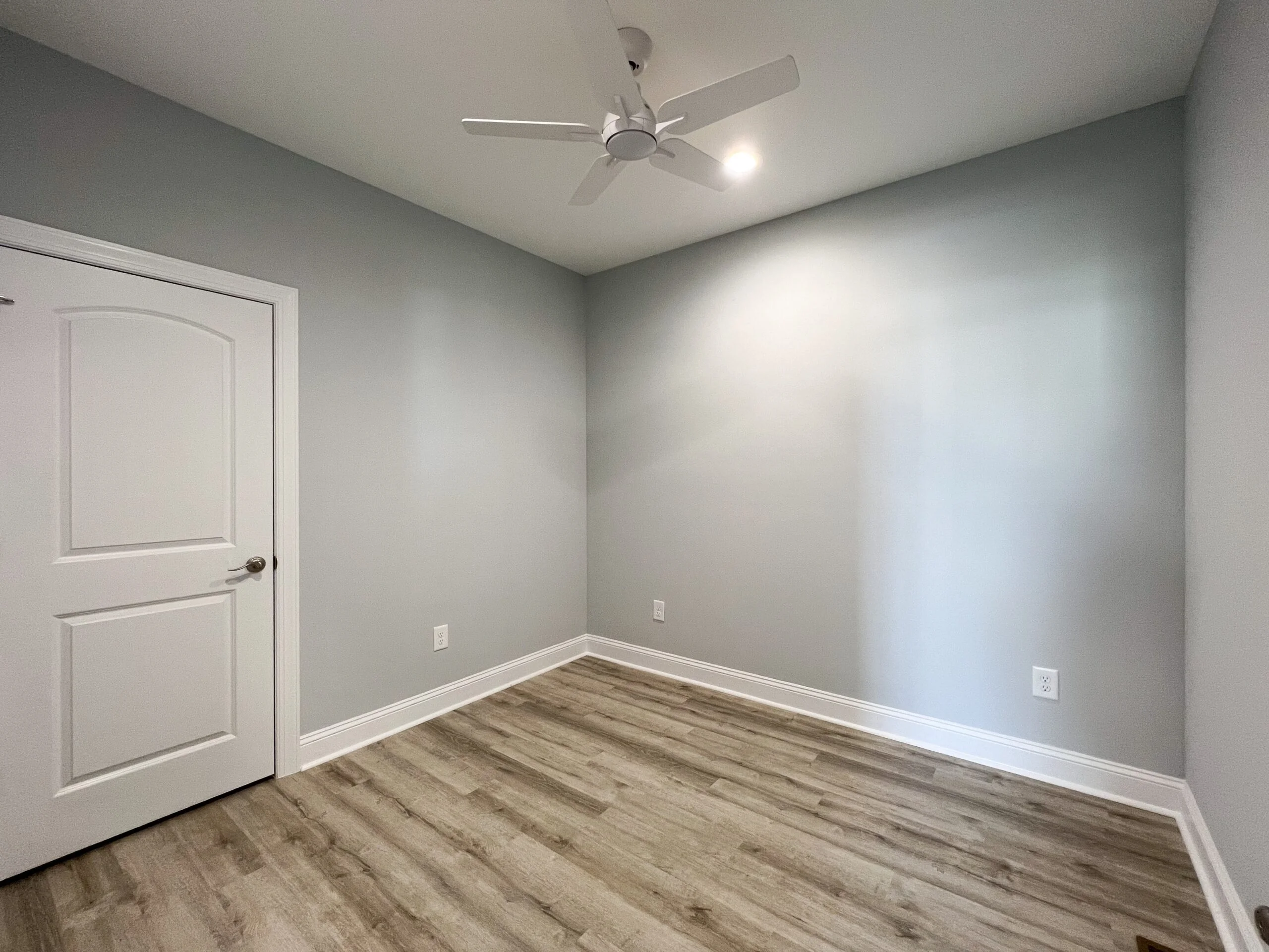 Finished bedroom with vinyl plank flooring, gray walls, white trim, and ceiling fan