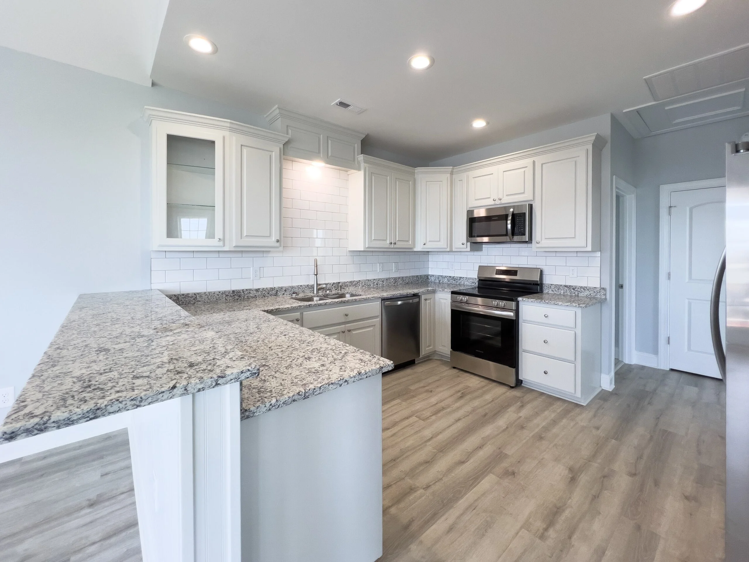 White kitchen cabinets, granite countertops, subway tile backsplash, stainless steel appliances